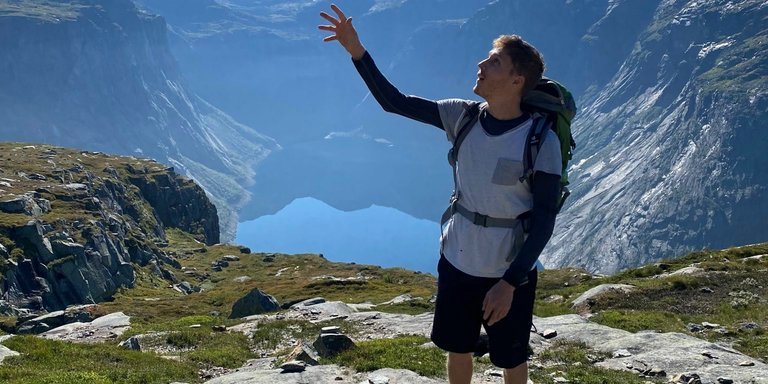 Kilian mit erhobener Hand über einem Bergsee