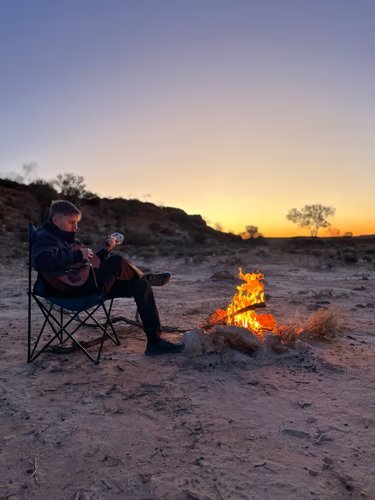 Kilian mit Gitarre am Lagerfeuer bei Sonnenuntergang